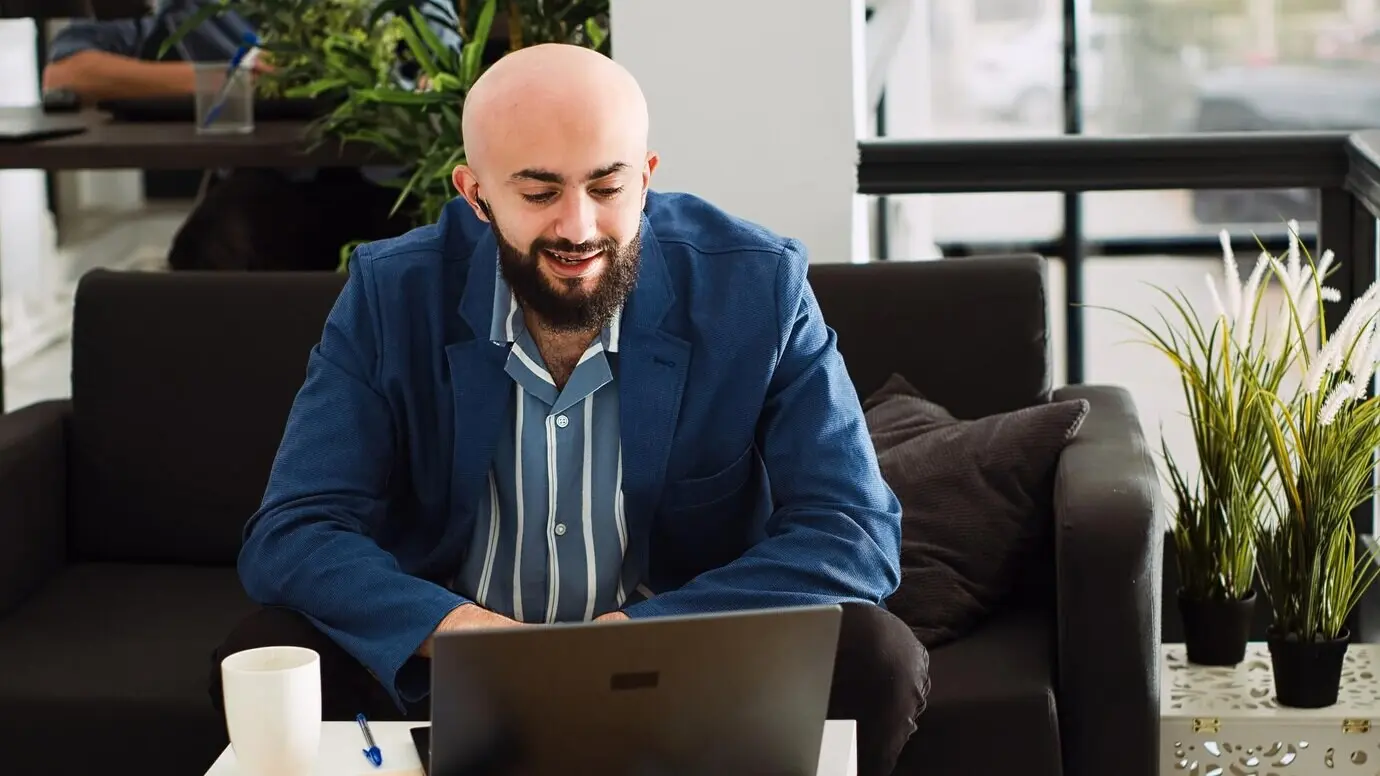 Разработчик ИИ использует деловой видеозвонок (брифинг), чтобы обсудить с менеджером изменения в разработке проекта. Молодой сотрудник стартапа на удалённом рабочем звонке. Съёмка с рук.